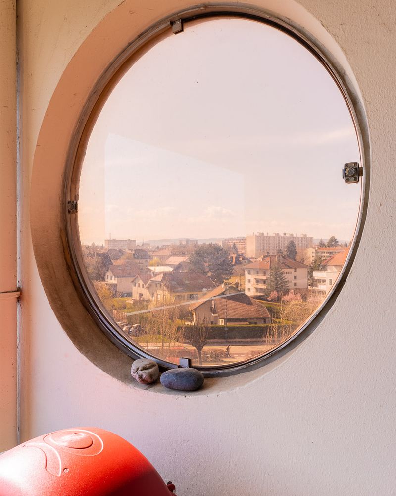 Fenêtre ronde ouvrant sur les toits d'Annecy, dans un penthouse à Annecy-le-Vieux