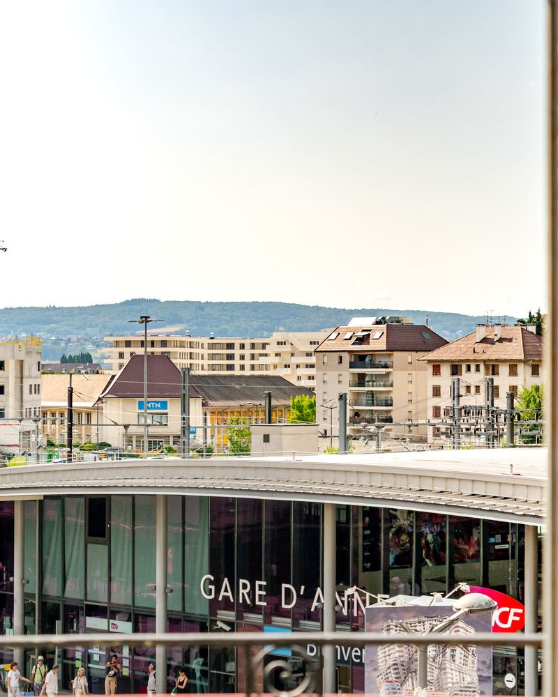 Vue sur la gare d'Annecy et les montagnes depuis un balcon